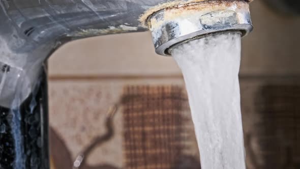 Water Flows From an Old Contaminated Tap with Calcium and Grime Into a Sink alt
