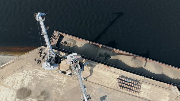 High Cranes Work with Breakstones at Docks, Unloading a Barge. alt
