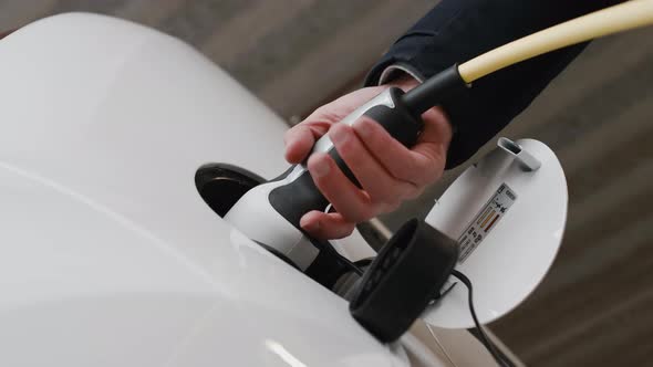 Man Plugging an Electric Car at the Electric Charging Station alt