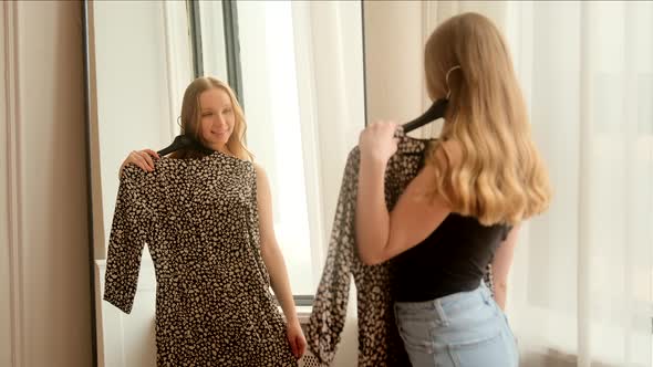 Woman getting dressed looking in mirror. Trying on dress clothes enjoying herself admires alt