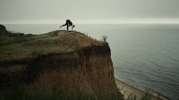 Sporty Girl Raise Foot to Sky Standing High Hill alt