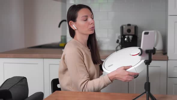 Millennial Girl Makes Online Review of Vacuum Cleaner at Home. Household Web Channel with Blogger alt