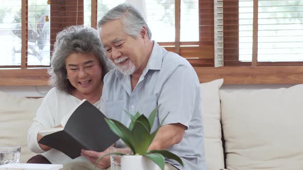 Senior couple reading book together on couch in living room