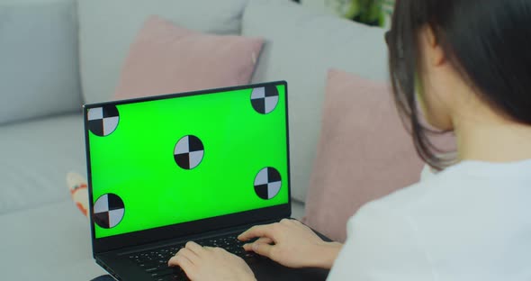 Young Asian Woman Lying on a Couch with Green Screen Laptop alt