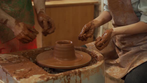 Pottery Training a Closeup of a Man Potter Teaches a Man How to Properly Mold a Bowl of Brown Clay alt