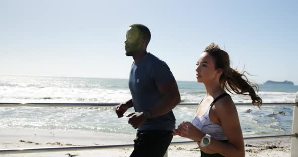 Fit couple jogging on a promenade at beach 4k