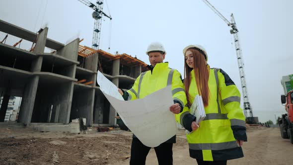 Female Architect and Male Foreman are Walking in Construction Site Discussing Building Plan alt