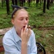 A Girl in a Blue Shirt Sits on a Bench in the Woods and Smokes a Cigar - VideoHive Item for Sale
