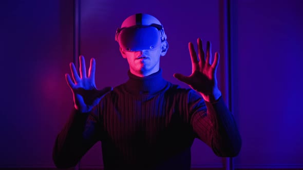 Young Man in a VR Helmet Interacts with Virtual Reality and 360 Media Content alt