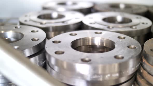 Shiny new stainless steel flanges piled on warehouse, market shelf, close up alt
