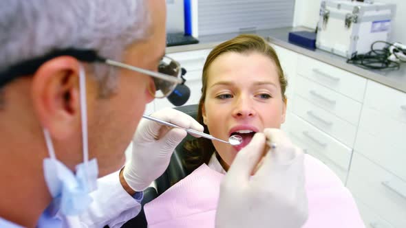 Dentist examining a female patient with tools alt