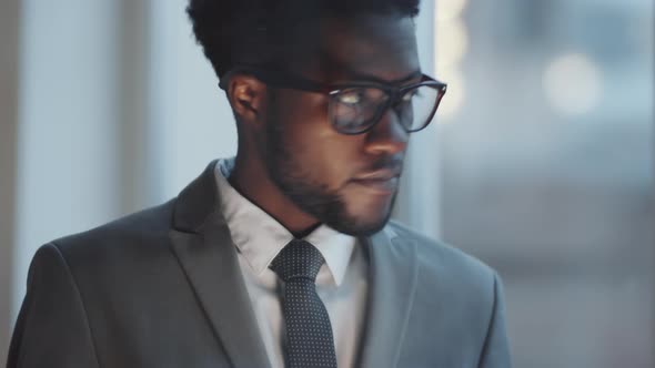 View through Office Glass Wall of Black Businessman Messaging on Smartphone alt