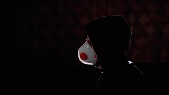 Silhouette of Man in Hood and Medical Mask Watching TV with Fake News. Covid-19 alt