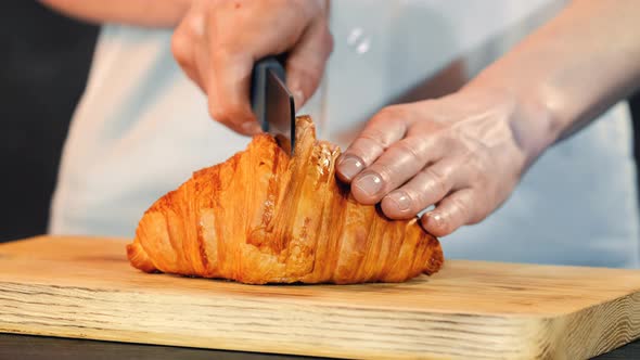 Close Up View Of Cutting Croissant With Knife