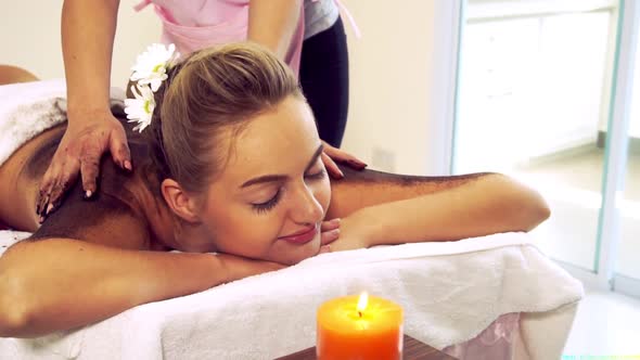 Relaxed Woman Lying on Spa Bed for Body Scrubbing Massage Using Traditional Herb alt