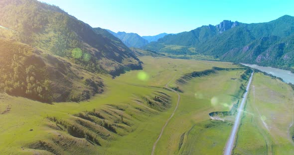Aerial Rural Mountain Road and Meadow at Sunny Summer Morning. Asphalt Highway and River. alt