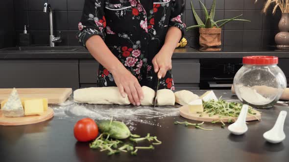 Female hands cutting raw dough into small pieces. alt