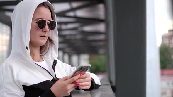 Stylish Young Girl Uses a Smartphone She is Wearing Sunglasses alt