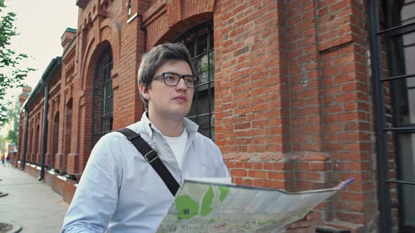 Gimbal Portrait Shot of Man Tourist with Map on Background City Red Birck Building