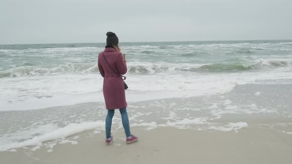 A Girl Stands on a Sandy Beach