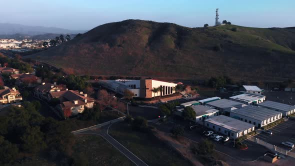 Aerial pull back shot of a a church at sunset in a suburban city. alt