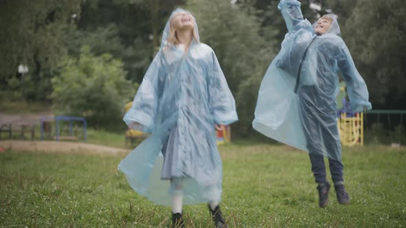 Wide Shot of Joyful Children Jumping and Catching Rain Drops with Mouth alt