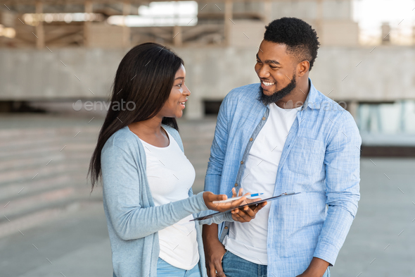 Black female volunteer conducting survey with young man on the street