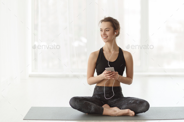 Sporty woman listening music in exercise outfit, practicing yoga