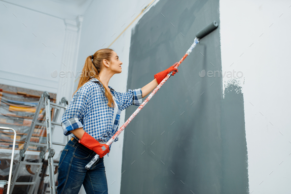 Female house painter in gloves paints the wall - Stock Photo - Images