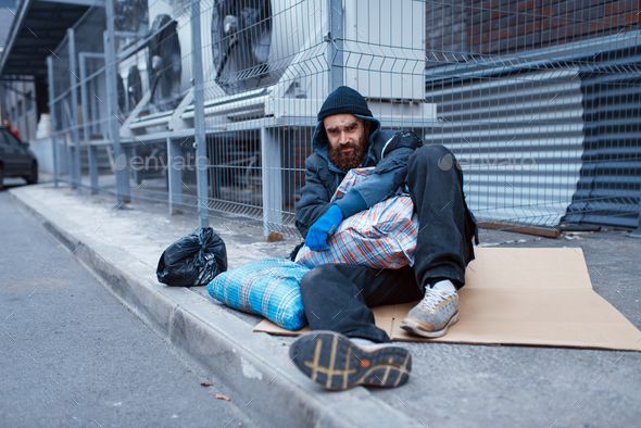Male bearded beggar lies on city street - Stock Photo - Images