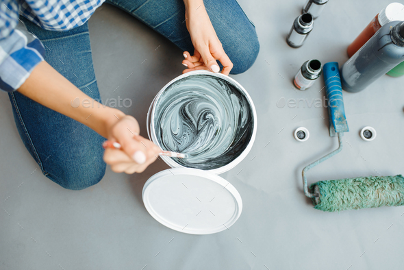 Female house painter mixes black and green paints - Stock Photo - Images