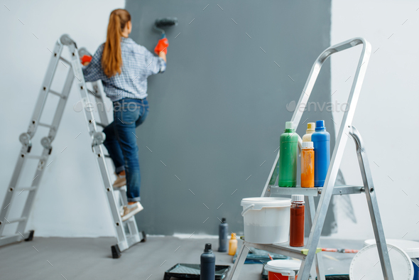 Female house painter paints walls indoor - Stock Photo - Images