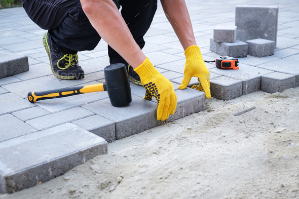 The master in yellow gloves lays paving stones - Stock Photo - Images