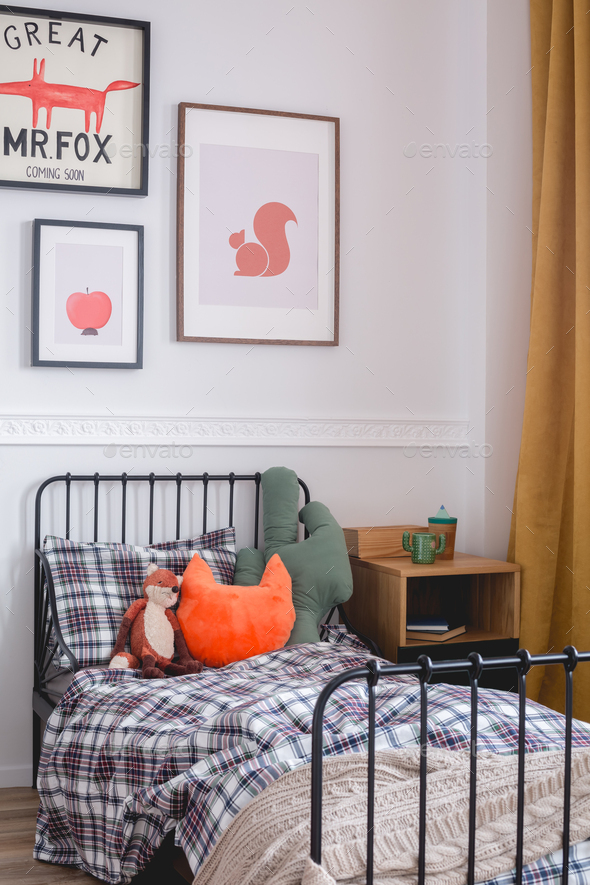 Pillows and toys on single metal bed in vintage bedroom interior for kid