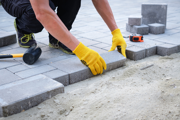 The master in yellow gloves lays paving stones - Stock Photo - Images