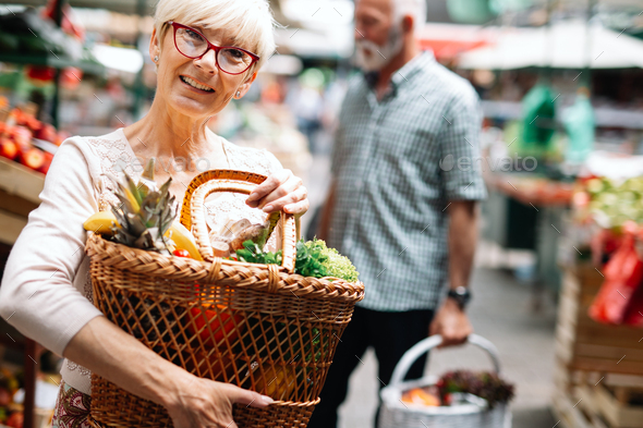 Picture of mature woman at marketplace buying vegetables