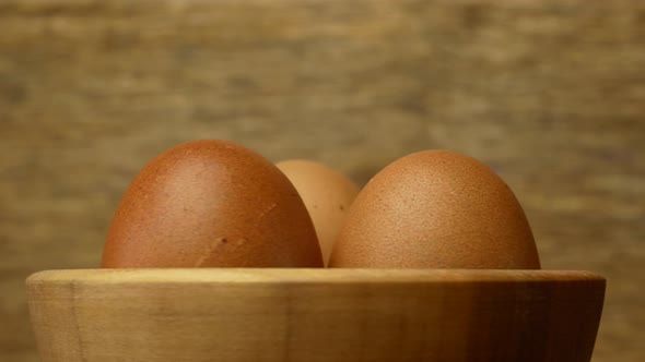 Rotation of eggs in a wooden plate on a wooden background. Easter concept.close up.Easter eggs alt