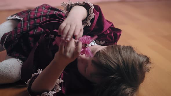 Cute Little Girl in Vintage Burgundy Dress is Playing with Hair Clip