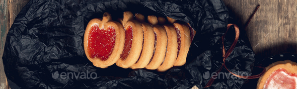 Banner of Cookie, biscuits filled with red raspberry jam on black table background.