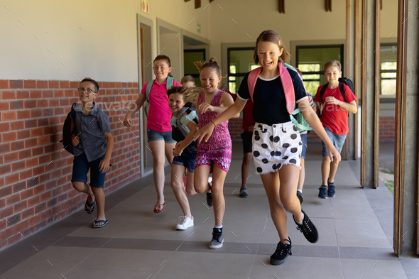 Group of schoolchildren running in an outdoor corridor at elementary school