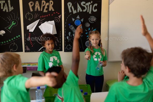 Group of schoolchildren wearing green t shirts with a white recycling logo on them