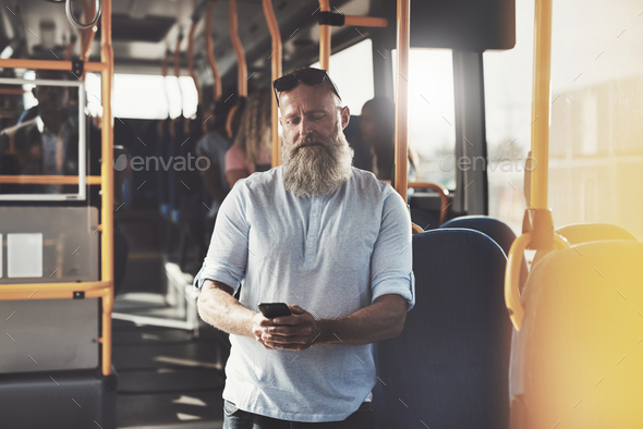 Mature man with a beard reading texts on the bus