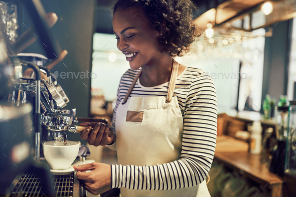 Smiling young African barista preparing coffee in a cafe