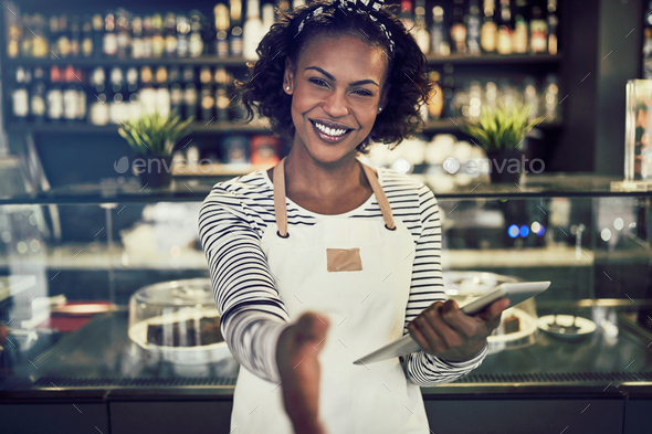 Smiling African hostess offering a handshake in her trendy cafe