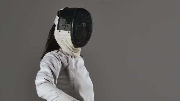 Portrait of Young Woman Fencer with Rapier in Her Hands Puts on and Then Removes Protective Mask on alt