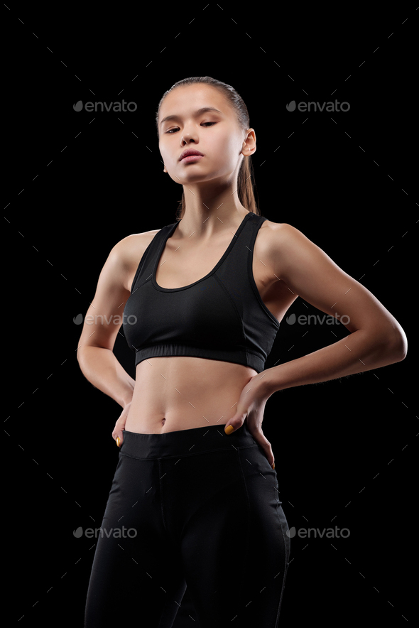 Young fit sportswoman keeping her hands on waist during physical training