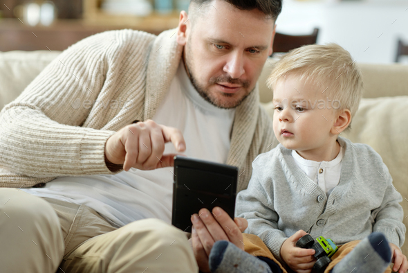 Father with boy using device on couch