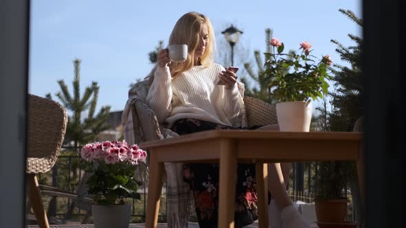 stylish woman enjoying tea while sitting on the terrace at home