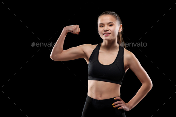 Happy sportswoman in black activewear showing her physical strength and muscles