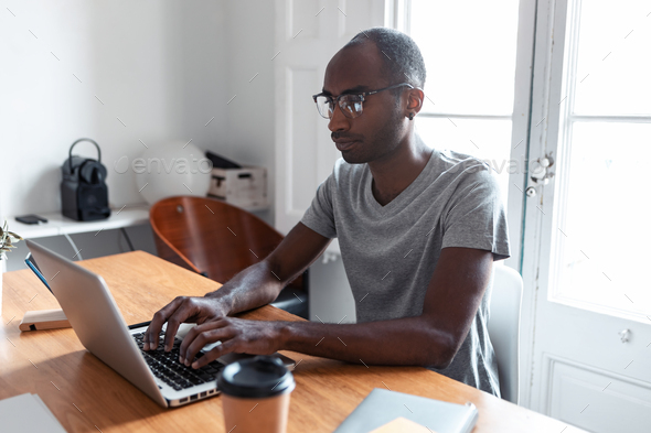 Concentrated young black business man working with laptop in the office.